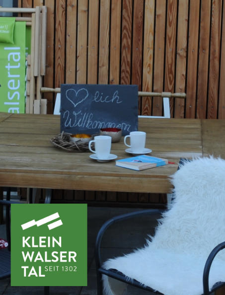 Ein Tisch mit Stühlen vor einer Holzhütte im Kleinwalsertal.